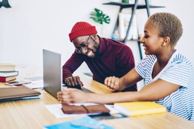 Neşeli koyu tenli hippi, dizüstü bilgisayardan güncellemeleri kontrol ediyor. Masaüstünde bayan meslektaşlarıyla öğreniyor. Genç Afrikalı Amerikalı adam internet mağazasının yanında oturan indirimlerden memnun.