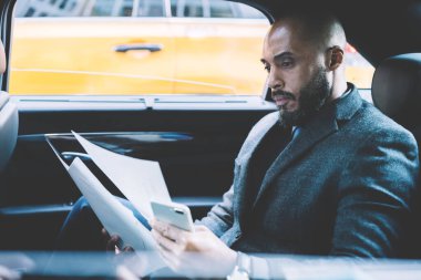 İş ortaklarıyla konferans toplantısına giden şirketin raporları hakkında resmi dava dosyalarını kontrol eden ciddi bir mali uzman, sözleşmeyle ilgili kağıt okuyan Afrikalı Amerikalı adam.