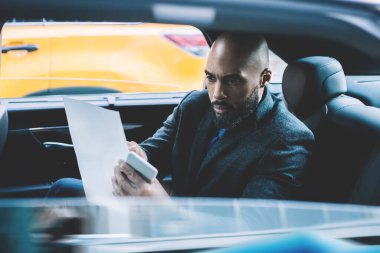 Zarif giyimli siyahi adam banliyö koltuğunda oturuyor ve şirket mali raporlarıyla uğraşarak zamanını harcıyor. Elinde kağıt tutarak strateji, iş dünyası konseptine odaklanıyor.