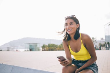 Şehir ortamında gülümseyen modern dijital cihazlı başarılı kadın blogcu e-postayla kendini iyi hissediyor. 4G kablosuz interneti cep telefonuyla kullanan gündelik kıyafetli bir kadın.