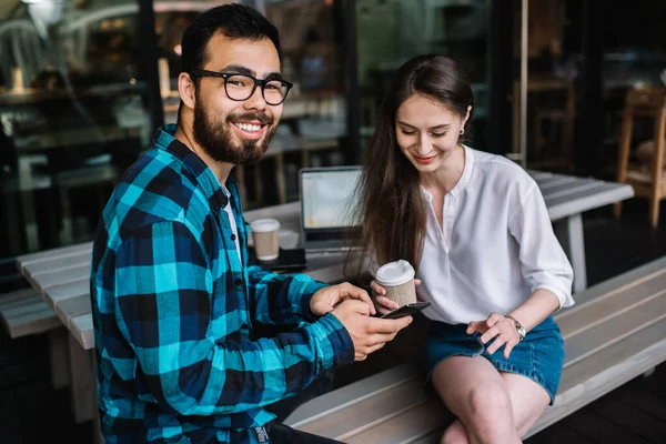 Birbirini seven pozitif çift internet sitesindeki yeni arkadaş paylaşımlarını okuyorlar. Modern akıllı telefon cihazında ücretsiz 4G internet bağlantısı kullanıyorlar. Açık havada kahve dükkanında oturuyorlar.