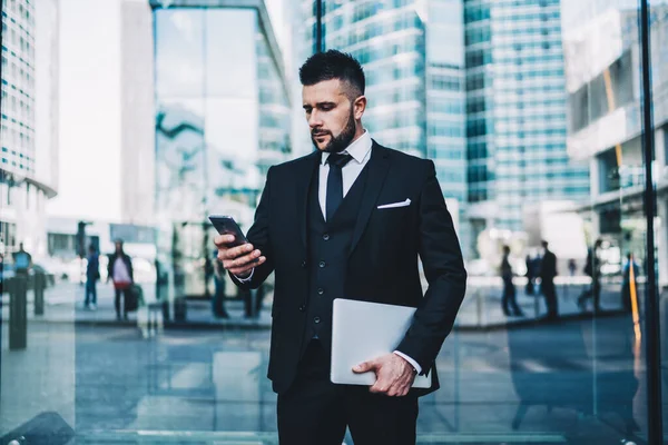 年轻的男性执行经理穿着时髦的正装 在户外使用手机 自信的商人穿着雅致的西装 通过连接到市中心4G互联网的智能手机发短信 — 图库照片