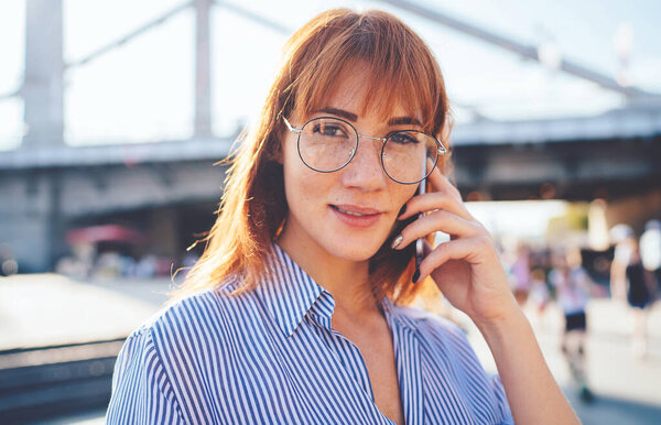 Крупный план портрета очаровательной молодой женщины в оптических очках консультации с оператором о роуминге связи для сотового телефона гаджет, Кавказский тысячелетие глядя в камеру и общаясь
