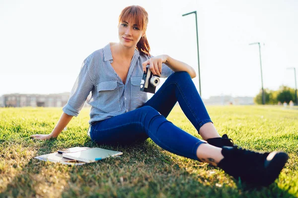 緑の芝生の上で休息を取り カメラを見て手にビンテージカメラ技術と魅力的な若い女性写真家の肖像画 美しい女性20歳趣味のための時間 — ストック写真