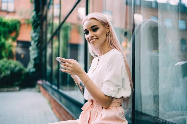 Portrait of cheerful woman with mobile phone in hands resting on urban setting with public internet connection, happy millennial hipster girl smiling at camera,concept of generation and digitalisation