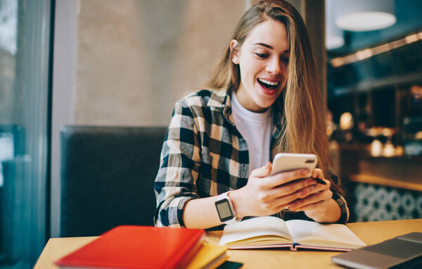 Счастливая девушка хипстера чувствует себя в шоке от полученной электронной почты с информацией о сессии университета, связанной с 4G беспроводной на мобильном телефоне, удивил студентку обмена сообщениями с ученым через приложение
