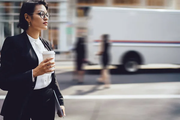 金融街で同僚を待っている間に離れて見てエレガントな服を着て深刻なビジネス女性 コーヒーと一緒に立って視力矯正のための眼鏡で自信を持って女性起業家行く — ストック写真