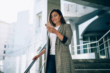 Başarılı bir kadın girişimci resmi ceket giyip internet sitesinde mesajlaşmanın keyfini sürerken akıllı telefon cihazıyla cevap veriyor. Cep telefonunda 4G kablosuz ağ kullanan genç bir kadın.