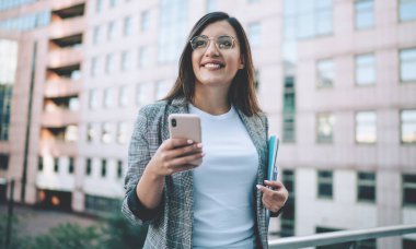 Resmi ceket giymiş, sosyal ağlardaki arkadaşlarla internet üzerinden iletişim kurarken cep telefonuyla milenyum konsepti üzerinden gülümseyen olumlu Türk bayan yöneticisi