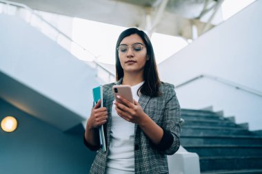 Röportaj bilgilerini not ettiği için ders kitabına bağlı ciddi kadın gazeteci toplantı zamanı ile e-postaları kontrol ettiği için, gözlüklü genç cep telefonu tebligatı okuduğu için