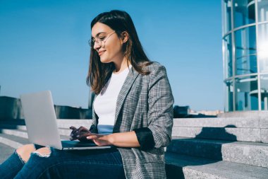 Laptop bilgisayarındaki uygulama ile posta kutusunu kontrol ederken göz falı bakılan pozitif uzaklık çalışanı, web sitesinde yayınlamak için içerik yaratan başarılı kadın