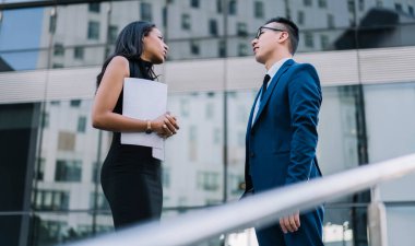 Çağdaş kadın ve erkeğin gazeteleri caddenin karşısında duruyor ve iş semineri sırasında konuşuyorlar.