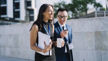 Çeşitli stil sahibi kadın ve erkek kimlikleriyle kahve içip sokakta yürürken akıllı telefonu paylaşıyor ve gün ışığında gülüyorlar.