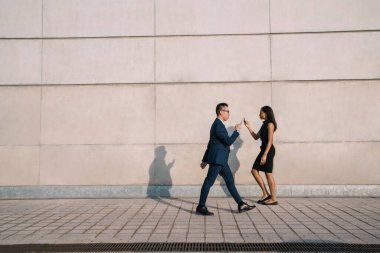 Gün ışığında sokakta yürürken akıllı telefonu dikkatsizce kullanan resmi kadın ve erkeğin yan görüntüsü