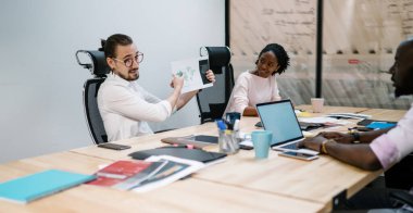 Konferans odasında ortaklarla birlikte çalışırken başarılı şirket ofislerinin haritasını gösteren zeki bir erkek çalışan, çeşitli meslektaşlar proje fikirlerini tartışıyor