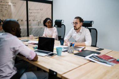 Erkek ve kadın ortaklar, bilişim projesi stratejisini tartışırken iş alanında birlikte çalışırlar. Konferans sırasında bilgiyi analiz eden çok kültürlü iş adamları.