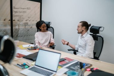 Çalışma saatleri boyunca konferans masasında birlikte çalışan çeşitli erkek ve kadın meslektaşlar, rapor oluşturma konusunda fikir alışverişinde bulunan çok kültürlü ortaklar,
