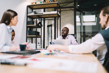 Atölyede çalışırken finansal raporun detaylarını tartışan çeşitli profesyonel ekonomistler, çalışanlar için motivasyon stratejisi konusunda işbirliği yapan akıllı yöneticilerden oluşan bir ekip