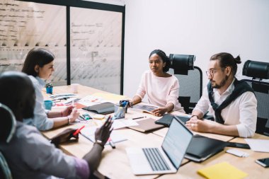 Resmi giyinmiş erkek ve kadın çalışanlar finans şirketinde birlikte çalışıyorlar, çok kültürlü insanlar beyin fırtınası sırasında finansal strateji üzerinde işbirliği yapıyorlar.