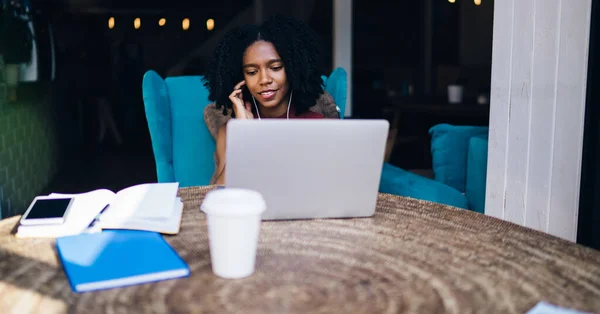 アフリカ系アメリカ人の女子学生は 勉強のためのマルチタスクの間にノートパソコンのコンピュータ上のアプリを介してビデオ通話を行うための休憩を楽しんで 若い女性はウェブサイト上でオンライン映画を見て — ストック写真