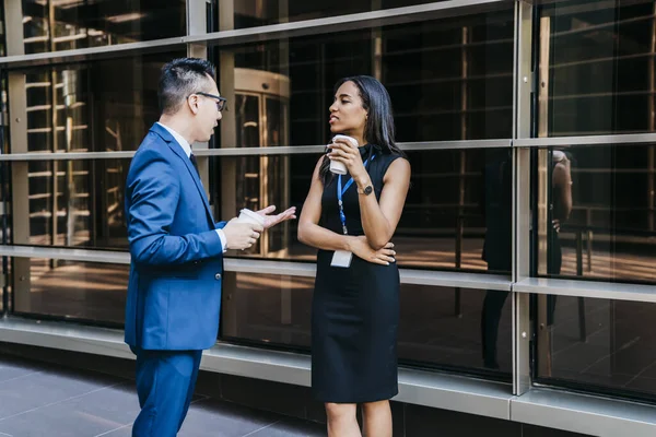 Contemporary African American woman and Asian man in formal clothes standing together on street having coffee being on break during conference meeting