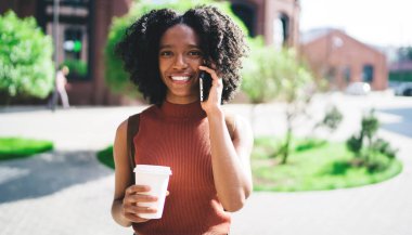 Elinde hazır fincanla neşeli yeniyetme kızın portresi akıllı telefon uygulaması yoluyla olumlu uluslararası sohbetin tadını çıkarıyor, kahve molası sırasında cep telefonuyla arayan mutlu bir kadın.