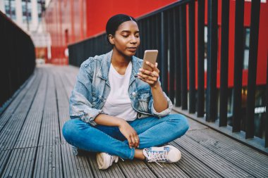 Koyu tenli kadın blogcu sosyal ağlardan yeni görüntüler okuyor cep telefonundan internete 4G bağlantısı kullanıyor, bin yıllık Afro-Amerikan kadın akıllı fonla mesaj gönderiyor.