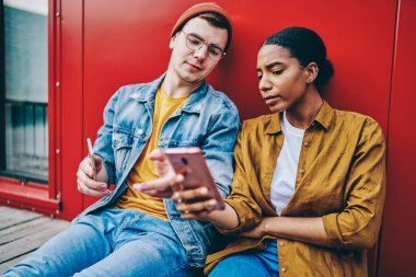 Pozitif Afro-Amerikalı bir kadın akıllı telefondan erkek arkadaşıyla iletişim kuran sosyal ağlardan çevrimiçi video gösteriyor, çok ırklı çift internet sayfasında cep telefonuyla haberleri okuyor ve 4