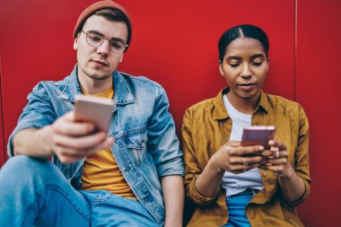 Modern akıllı telefonlar ve 4G internet bağlantısı ile sosyal ağlarda sohbete başlamadan önce gerçek sohbeti görmezden gelen çok ırklı hippi kız ve erkek birlikte oturuyorlar.