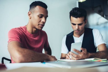 Çeşitli erkek arkadaşlar, birlikte zaman geçirmek için akıllı telefon uygulaması için uyarı mesajı okuyorlar, 4G kablosuz internete bağlı internet sitesinde video izleyen yakışıklı hippi adamlar.