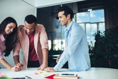 Birlikte çalışma ofisinde iş planı ve stratejileri tartışan neşeli çok ırklı meslektaşlar, mutlu erkek ve kadınlar beyin fırtınası yaparak zaman geçiriyorlar, üretken iş kavramı.