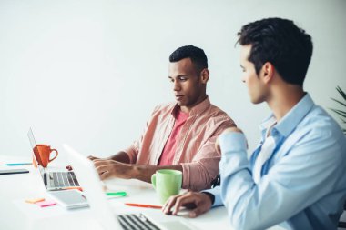 Gelişigüzel giyinen yetenekli erkek programcılar, ofis içi 4G kablosuz internete bağlı dizüstü bilgisayardaki yeni uygulama için tasarım üzerinde işbirliği yapıyorlar.
