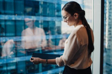 Çağdaş ofis binasının penceresinde elinde kağıt belge ile gülümseyen zarif bir kadının yan görünümü 