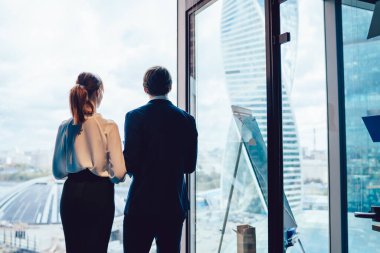 Modern zarif kadın ve erkeğin pencereye karşı yan yana durup, ofiste çalışırken motivasyonla bakışlarının arkası.