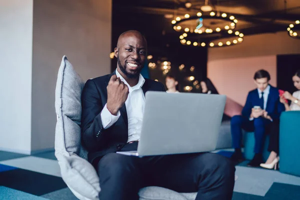 Junger Lächelnder Schwarzer Mann Anzug Sitzt Mit Erhobenem Laptop Sessel — Stockfoto
