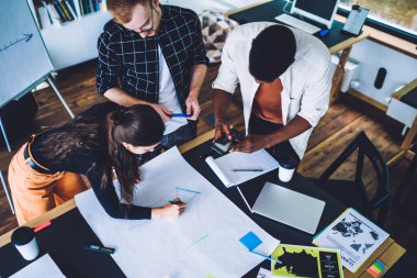 Masada duran ve kağıt üzerinde yeni bir proje üzerine tartışan çok ırklı kadın ve erkeklerden. 