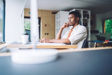 Modern ışık ofisindeki masada oturan yakışıklı siyahi adamın yan görünüşü ilham ve tefekkür ile gözlerini kaçırıyor.