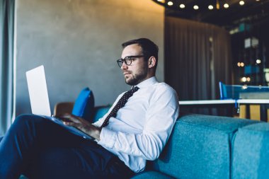 Portatif netbook 'ta 4G bağlantısı kullanarak internet sitesinde finans haberleri okuyan yetişkin işadamlarının yan görüntüsü, resmi giyimde erkek uzman koltukta oturuyor ve uygulama yüklüyor