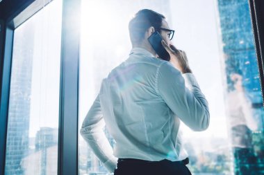 Girişimcilik şirketinde iş arkadaşlarıyla cep telefonuyla konuşan erkek girişimcinin arka planda görüşü, iş ortaklarıyla iletişim kurmak için cep telefonunda 4G internet kullanan bir tüccar.