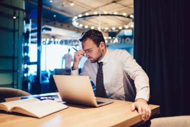 Masaüstünde oturup şirket için finansal stratejiyle ilgili sorunları çözen beyaz bir adam, girişimcilik inşaatında son teslim tarihini yaşıyor.