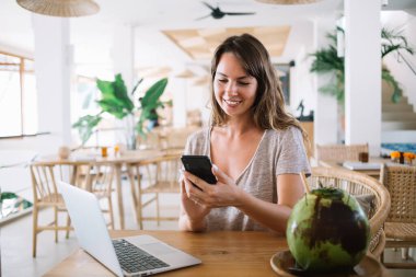 Elinde cep telefonu cihazı olan, sosyal ağlarda içerik blogunda komik metin yayınları okuyan, Endonezya internetini taramak için kullanan neşeli kadın serbest yazar.