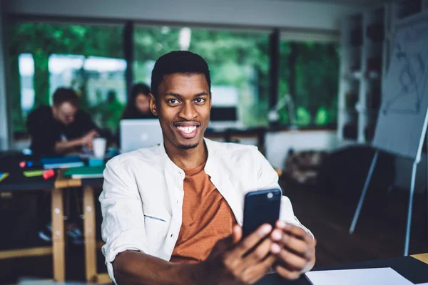 Joven Hombre Afroamericano Casual Sonriendo Mientras Está Sentado Escritorio Trabajo — Foto de Stock