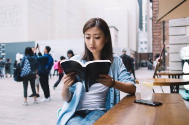 Düşünceli esmer kadın elinde kitapla sokaktaki ilginç roman senaryolarına odaklanmış. Çekici hippi kız, en çok satanlar listesinin en iyilerini inceleyerek şehir ortamında zaman harcıyor.