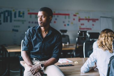 Genç Afrikalı kendine güvenen yönetici ofis masasında oturup patronla, muhasebe ve iş dünyasıyla görüşmeyi beklerken gözlerini kaçırıp şirket stratejisi üzerine kafa yoruyor.