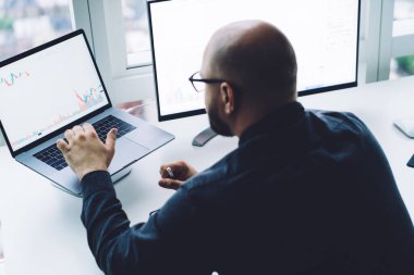 Gözlüklü bulanık kel adamın dizüstü bilgisayarı ile ofiste pencereye karşı oturması. 