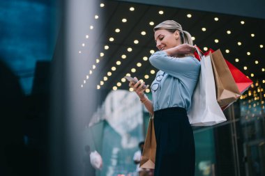 İnternet mağazası servisinden geri bildirim bekleyen olumlu kadın müşteri, akıllı telefon aracılığıyla satın alınmayı bekliyor. Alış veriş sırasında internet sayfasında internet üzerinden sohbet eden neşeli kadın.