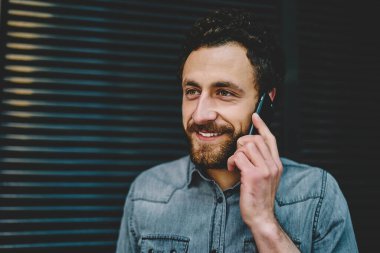 Neşeli sakallı hippi adam dışarıda telefonla konuşuyor. Kafkasyalı yakışıklı erkek cep telefonu konuşmasından memnun. Aramak için iyi cep telefonu tarifeleri var.