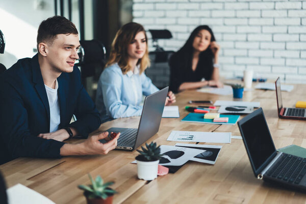 Young crew of male and female coworkers working together in modern office planning finance side of company, intelligent partners sitting at desk and discussing ideas for productive business strategy