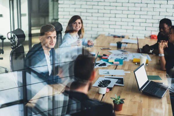 Mutlu erkek ve kadın meslektaşlar, patronla toplantı arasında modern ofiste iletişim kurdular, başarılı ortaklar masada oturdular ve birlikte iş birliği yaparken proje fikirlerini tartıştılar.