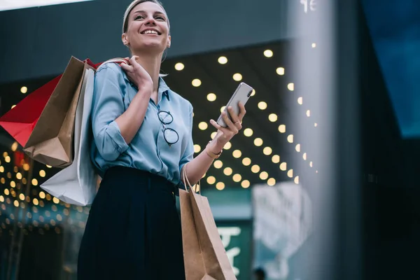快乐的女性顾客 纸袋等待着网上购物服务的反馈 兴奋的女性购物狂 手持智能手机设备 从社交网络上有趣的出版物中开怀大笑 — 图库照片